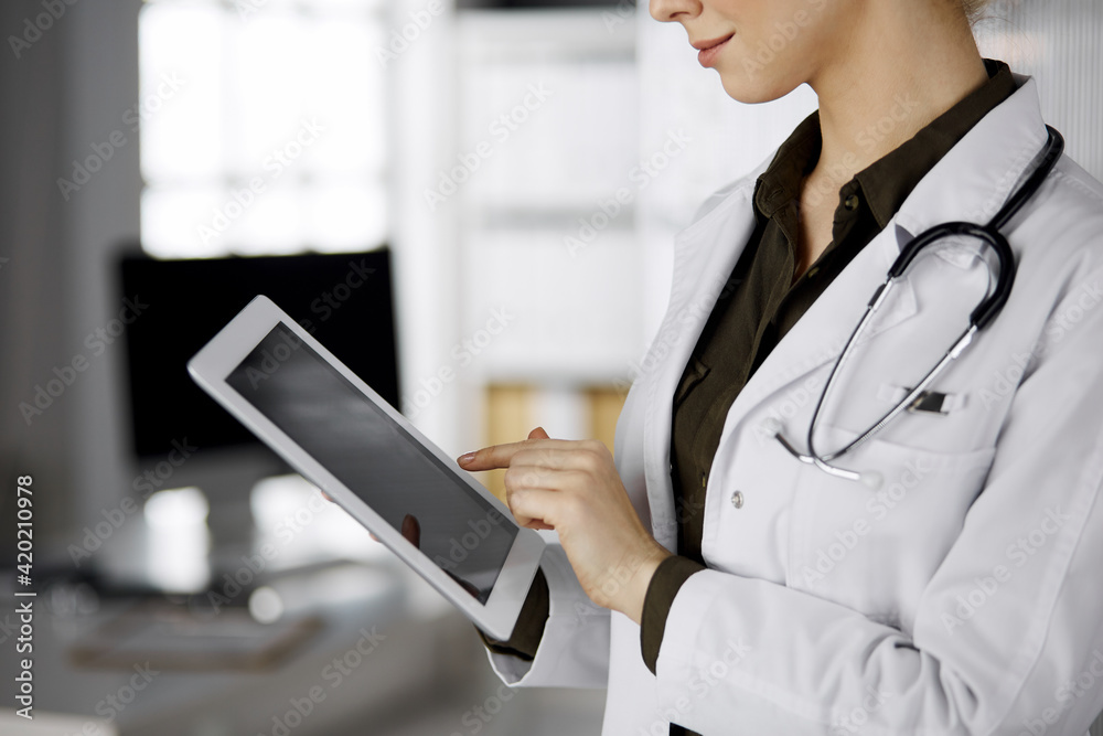 Unknown female doctor using tablet computer in clinic. Perfect medical service in hospital. Medicine concept Unknown female doctor using tablet computer in clinic. Perfect medical service in hospital. Medicine concept