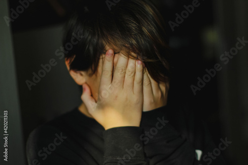 boy covers his face with his hands
