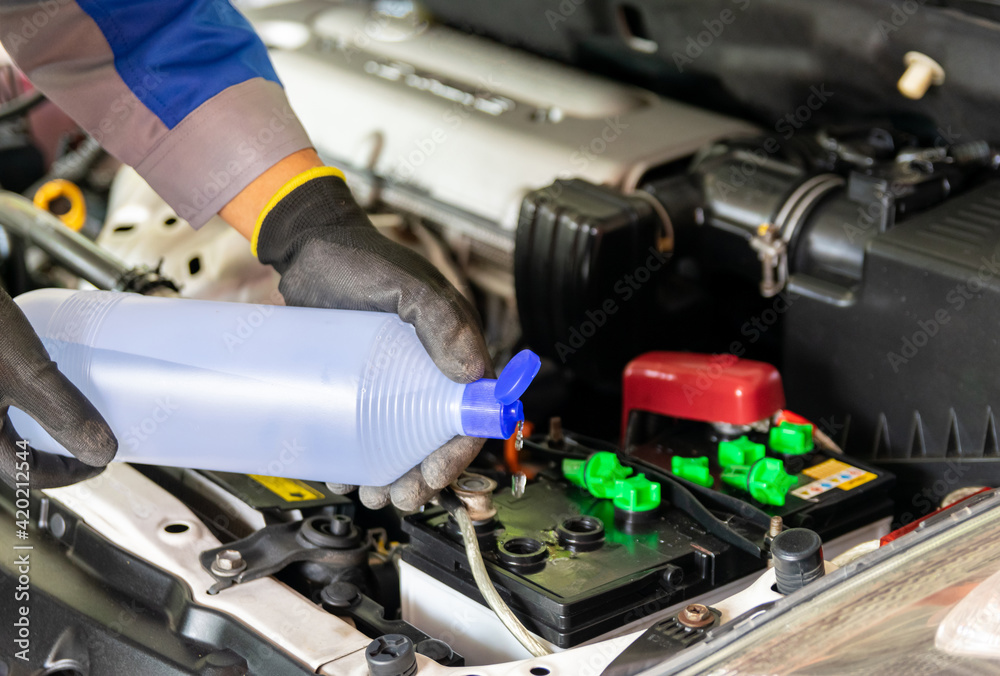 The mechanic adds distilled water and check the car battery The mechanic adds distilled water and check the car battery