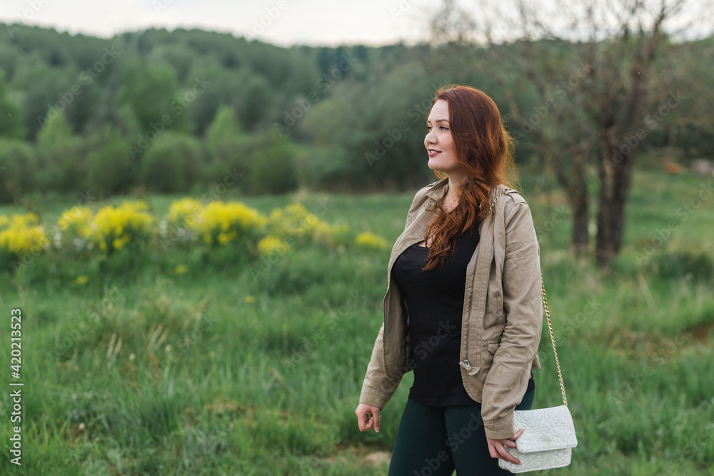Young woman enjoying blooming spring in a forest walking. Green grass and yellow flowers in the meadow Young woman enjoying blooming spring in a forest walking. Green grass and yellow flowers in the meadow