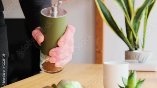 Making speciality coffee at home. Barista grinds fresh coffee in a manual grinder. Aromatic filter coffee on the table. Breakfast. Coffee break.