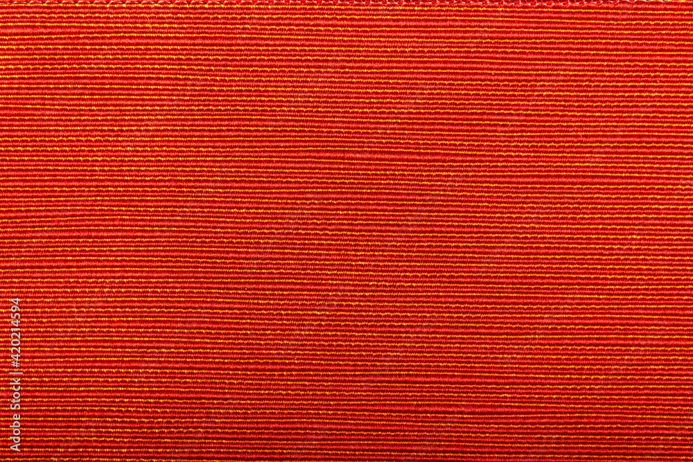 Fototapeta premium Factory fabric of red color with yellow threads interspersed. Close-up long and wide texture of natural red fabric. Fabric texture of natural cotton or linen textile material. Red canvas background