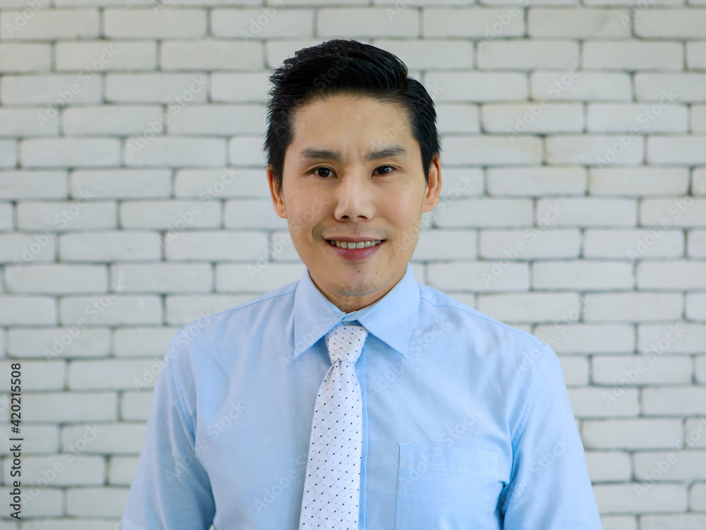 Portrait of young and handsome Asian man wearing shirt and tie with smile and happy friendly face on white brick wall background. Portrait of young and handsome Asian man wearing shirt and tie with smile and happy friendly face on white brick wall background.