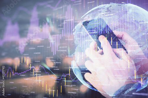 Double exposure of man's hands holding and using a digital device and forex graph drawing. Financial market concept.