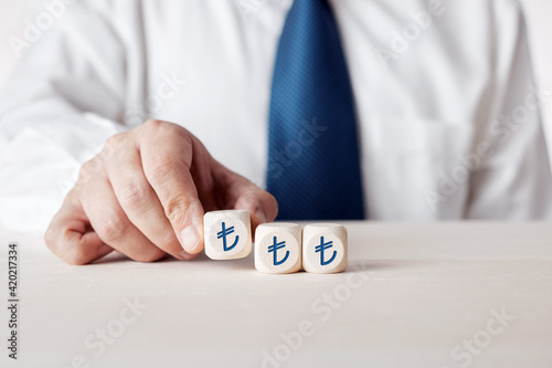 Hand of a businessman placing the wooden cubes with Turkish lira symbol.