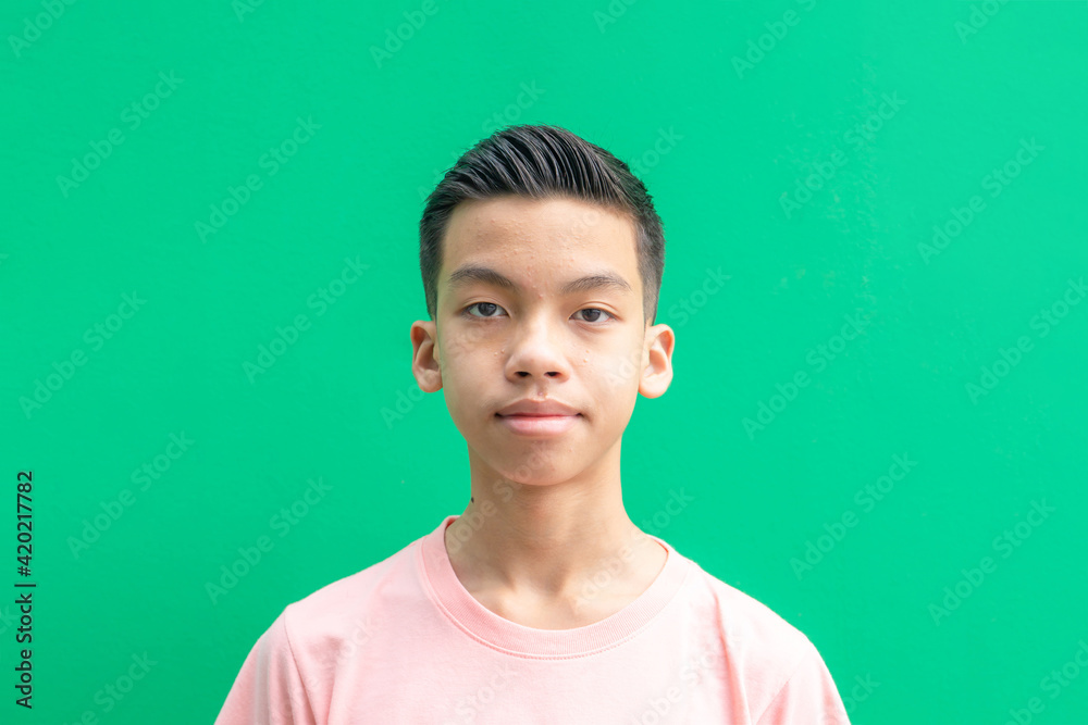 Portrait of asian teenage boy looking at camera on green background.
