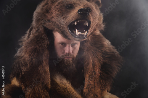 Vászonkép Low key portrait of a bearded war shaman in bearskin with an ancient ax in his hands