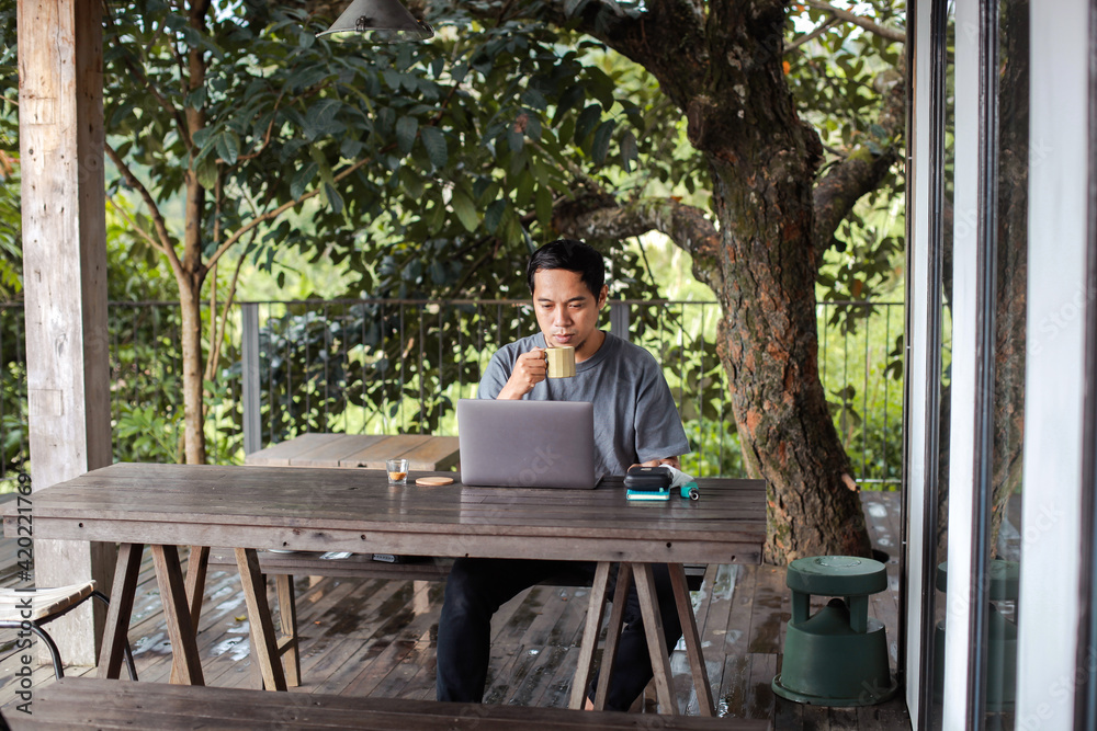 Fototapeta premium Man sitting and drinking coffee while working with laptop