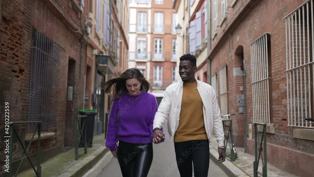 Diversity concept. Interracial couple holding hands walking outside in european street Diversity concept. Interracial couple holding hands walking outside in european street