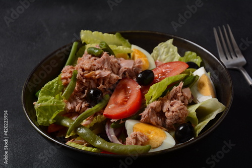 Salad Nicoise. French cuisine. Healthy salad of tuna, green beans, tomatoes, eggs, potatoes, black olives close-up in a bowl on the table.