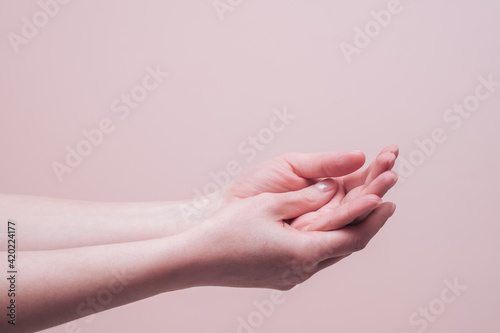 Female hands on pink background. Closeup  copy space. Cosmetology and skin care concept