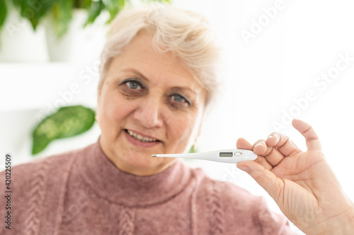 Smiling senior woman shows thermometer