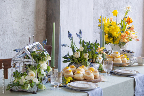 Choux Buns with Craquelin (crispy cream puffs) filled cream on a table decorated with spring flowers
