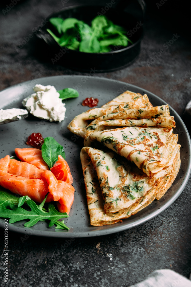 Thin pancakes with herbs, salmon and cream cheese on a plate. crepes Thin pancakes with herbs, salmon and cream cheese on a plate. crepes