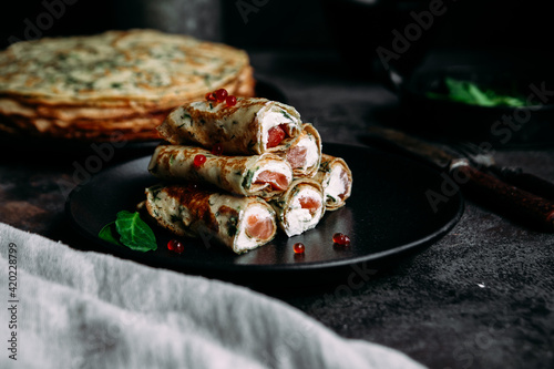 Thin pancakes with herbs  salmon and cream cheese on a plate. crepes