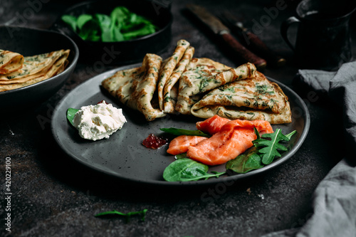 Thin pancakes with herbs, salmon and cream cheese on a plate. crepes