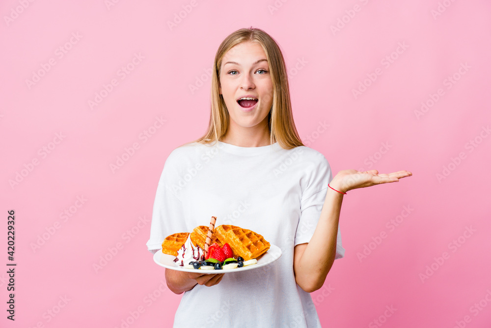 Young russian woman eating a waffle isolated surprised and shocked. Young russian woman eating a waffle isolated surprised and shocked.