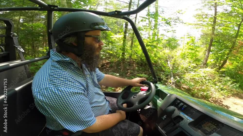 bearded man driving utv through forest and under fallen tree sunny pov passenger view bearded man driving utv through forest and under fallen tree sunny pov passenger view
