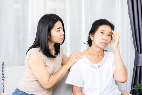 Asian daughter comforting, supporting her depressed, sad mother sitting together at home © doucefleur