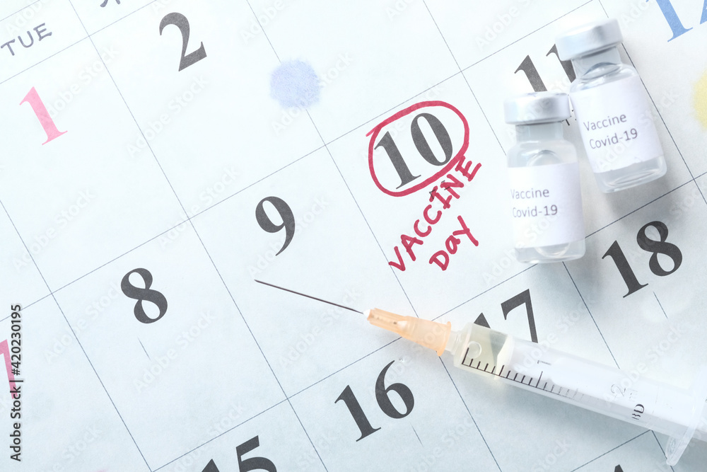 Fototapeta premium coronavirus vaccine and syringe on calendar background