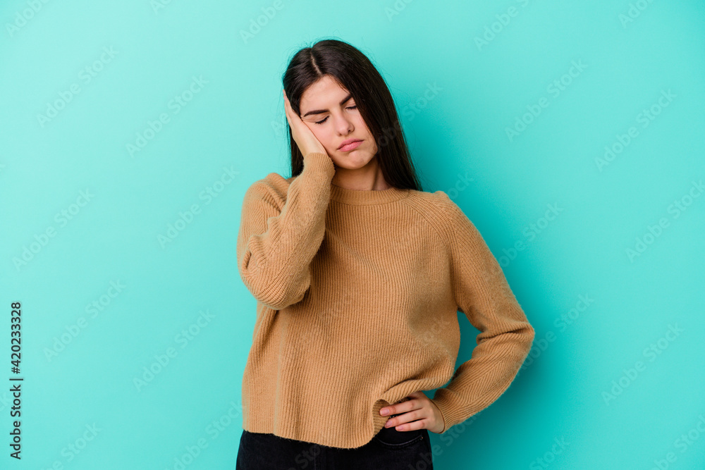 Young caucasian woman isolated on blue background who is bored, fatigued and need a relax day. Young caucasian woman isolated on blue background who is bored, fatigued and need a relax day.