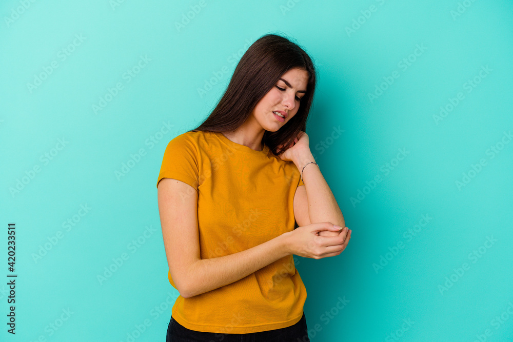 Young caucasian woman isolated on blue background massaging elbow, suffering after a bad movement. Young caucasian woman isolated on blue background massaging elbow, suffering after a bad movement.
