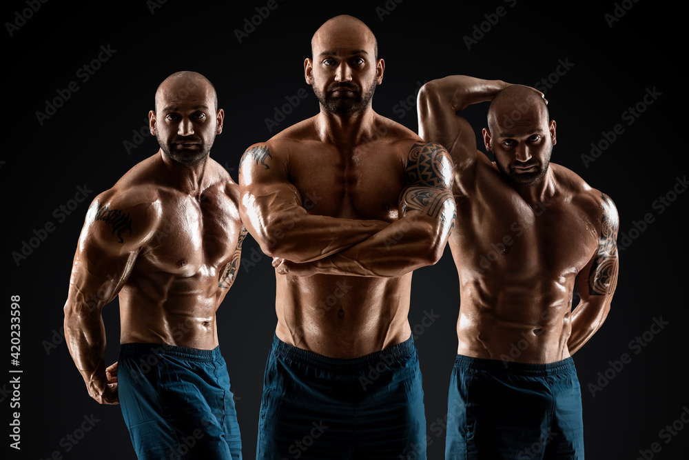 Male bodybuilder with light stubble and bare torso shows muscularity against a dark background. The concept of a fitness club, doing sports, weightlifting. Copy space. Male bodybuilder with light stubble and bare torso shows muscularity against a dark background. The concept of a fitness club, doing sports, weightlifting. Copy space.