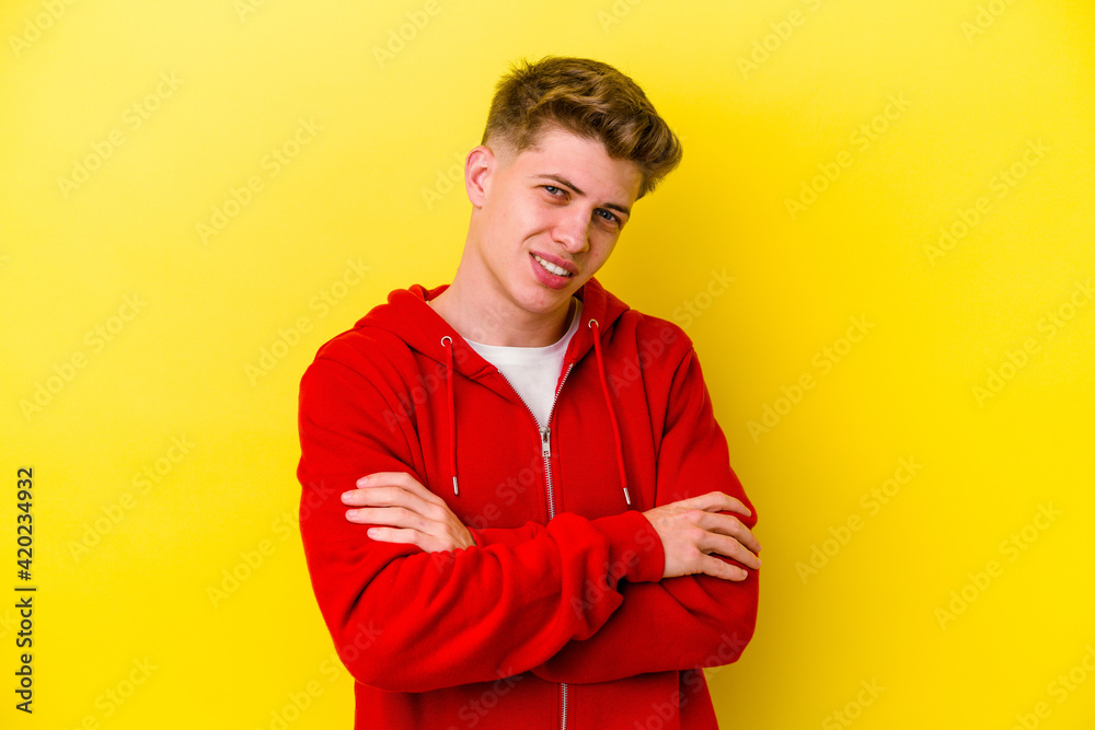 Young caucasian man isolated on yellow background who feels confident, crossing arms with determination. Young caucasian man isolated on yellow background who feels confident, crossing arms with determination.
