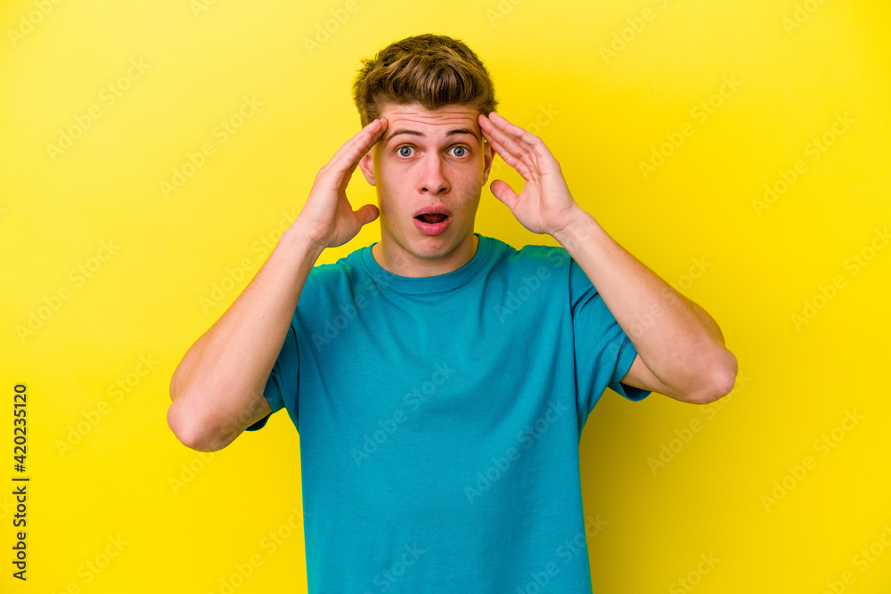 Young caucasian man isolated on yellow background having fun covering half of face with palm.