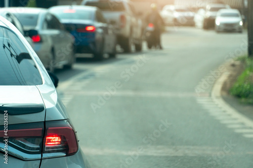 Transportation of white car on the road.  On the asphalt road. Queue with many cars and turn on the brake lights. Blurred road with curves. © thongchainak