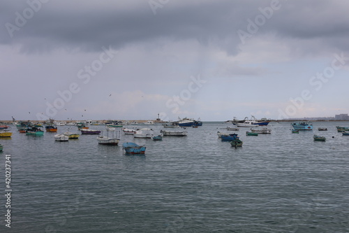 Boats in the harbor. View from coast in Mediterranean Sea. Scenic landscape on a rainy day. Heavy rain clouds. Beautiful Egyptian horizon with a lot of little fishing boats 