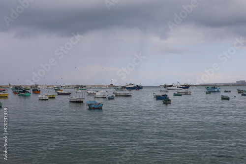 Boats in the harbor. View from coast in Mediterranean Sea. Scenic landscape on a rainy day. Heavy rain clouds. Beautiful Egyptian horizon with a lot of little fishing boats 