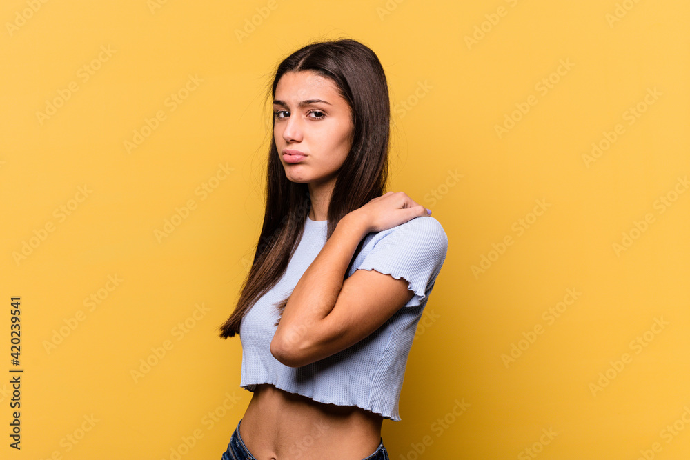 Young Indian woman isolated on yellow background having a shoulder pain. Young Indian woman isolated on yellow background having a shoulder pain.