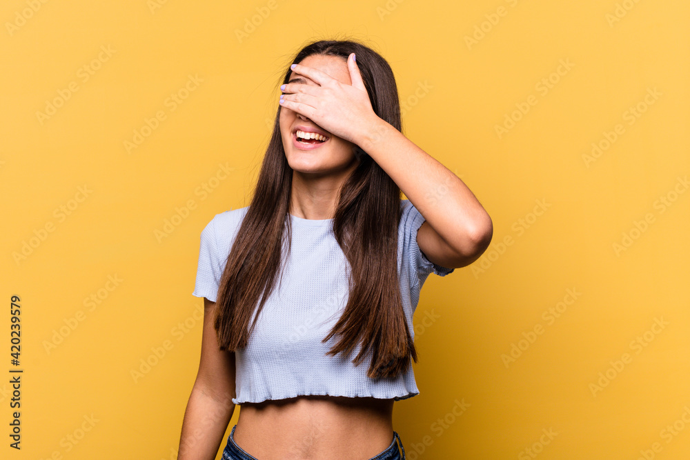 Young Indian woman isolated on yellow background covers eyes with hands, smiles broadly waiting for a surprise. Young Indian woman isolated on yellow background covers eyes with hands, smiles broadly waiting for a surprise.