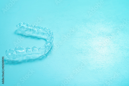 Invisible dental teeth brackets tooth aligners on turquoise background. Plastic braces dentistry retainers to straighten teeth. © johnalexandr