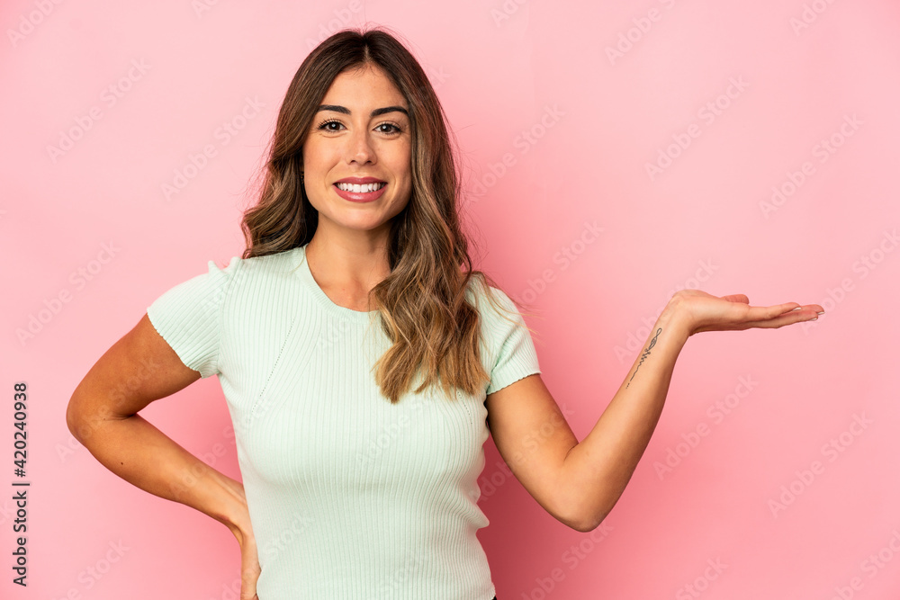 Young caucasian woman isolated showing a copy space on a palm and holding another hand on waist. Young caucasian woman isolated showing a copy space on a palm and holding another hand on waist.