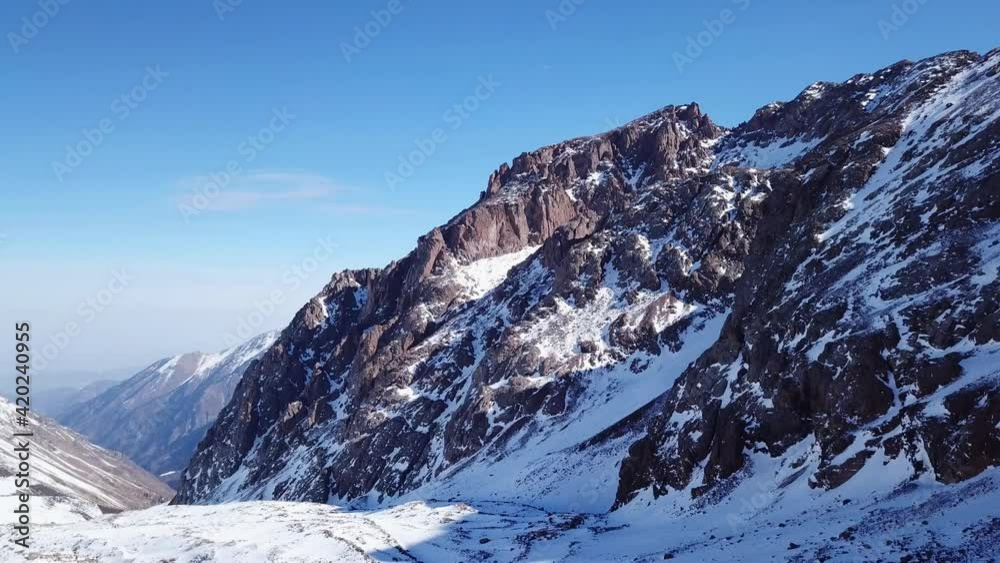 High snow-capped peaks and glaciers. Top view from the drone. Steep cliffs, the wind blows away the snow. There is a lone nunatak. Moraine frozen lake. Climb to the peak. Bogdanovich Glacier, Almaty High snow-capped peaks and glaciers. Top view from the drone. Steep cliffs, the wind blows away the snow. There is a lone nunatak. Moraine frozen lake. Climb to the peak. Bogdanovich Glacier, Almaty