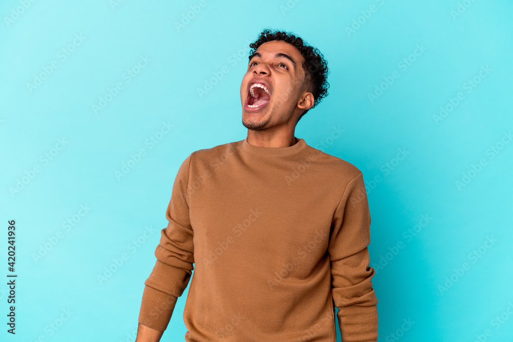 Young african american curly man isolated on blue shouting very angry, rage concept, frustrated.