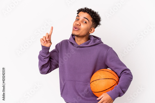 Young african american curly man isolated playing basketball having some great idea, concept of creativity. © Asier