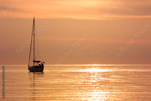 sailing boat silhouette in the distance in a calm orange glowing seamless sea.Sunset on the Adriatic Sea © Studio 888