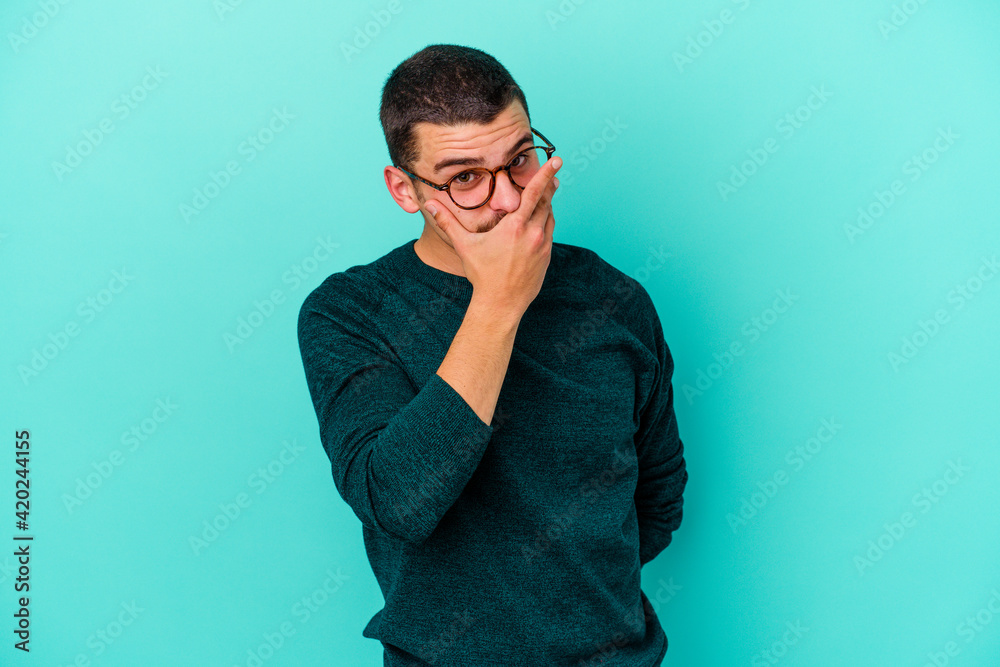 Young caucasian man isolated on blue background scared and afraid.