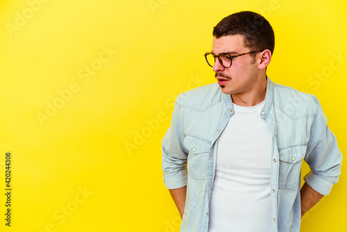 Young caucasian cool man isolated on yellow background being shocked because of something she has seen.