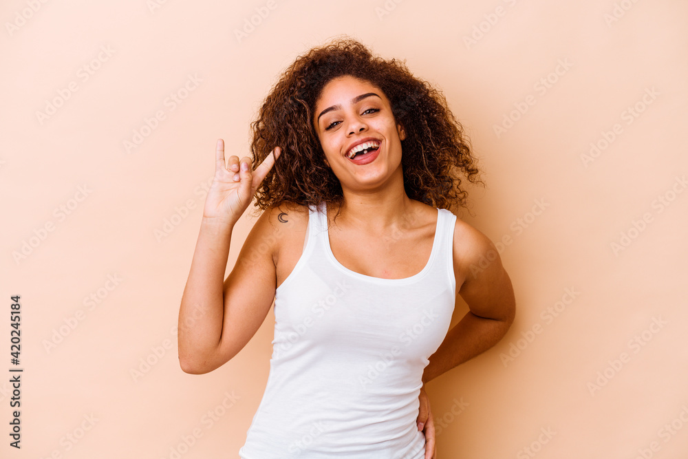 Fototapeta premium Young african american woman isolated on beige background showing a horns gesture as a revolution concept.