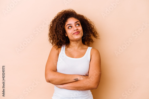 Young african american woman isolated on beige background dreaming of achieving goals and purposes © Asier