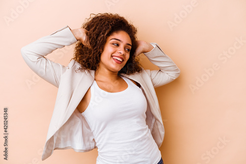 Young african american woman isolated on beige background feeling confident, with hands behind the head. © Asier