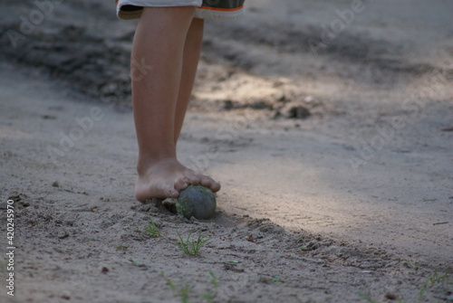 The child plays ball with bare feet. Belarusian village.
