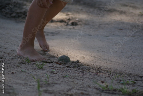 The child plays ball with bare feet. Belarusian village.
