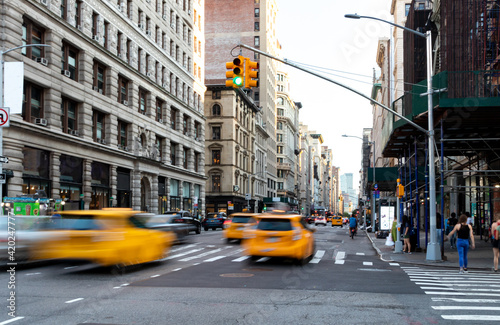Yellow taxis driving down the street on Fifth Avenue through the busy intersections in Midtown Manhattan New York City NYC © deberarr