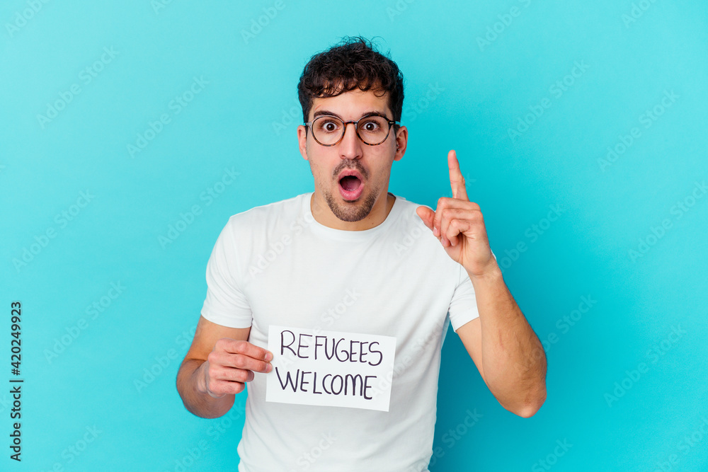 Young caucasian man holding a Refugees welcome placard isolated having an idea, inspiration concept. Young caucasian man holding a Refugees welcome placard isolated having an idea, inspiration concept.