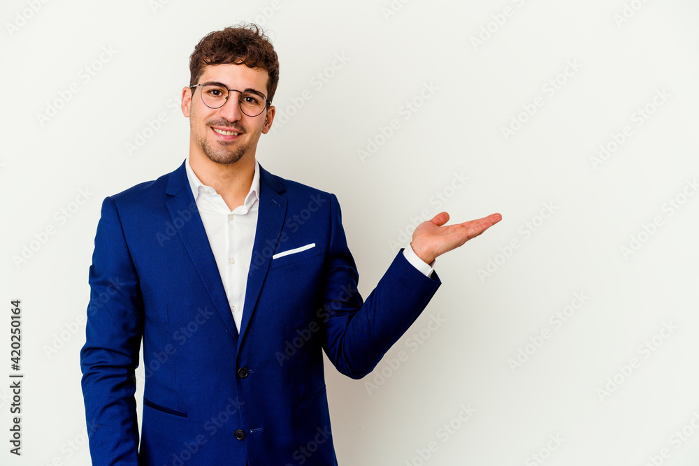 Young business caucasian man isolated on white background showing a copy space on a palm and holding another hand on waist. Young business caucasian man isolated on white background showing a copy space on a palm and holding another hand on waist.